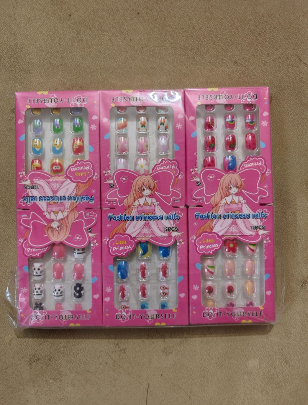 Set of pink nail art kits with cartoon character on a cardboard background