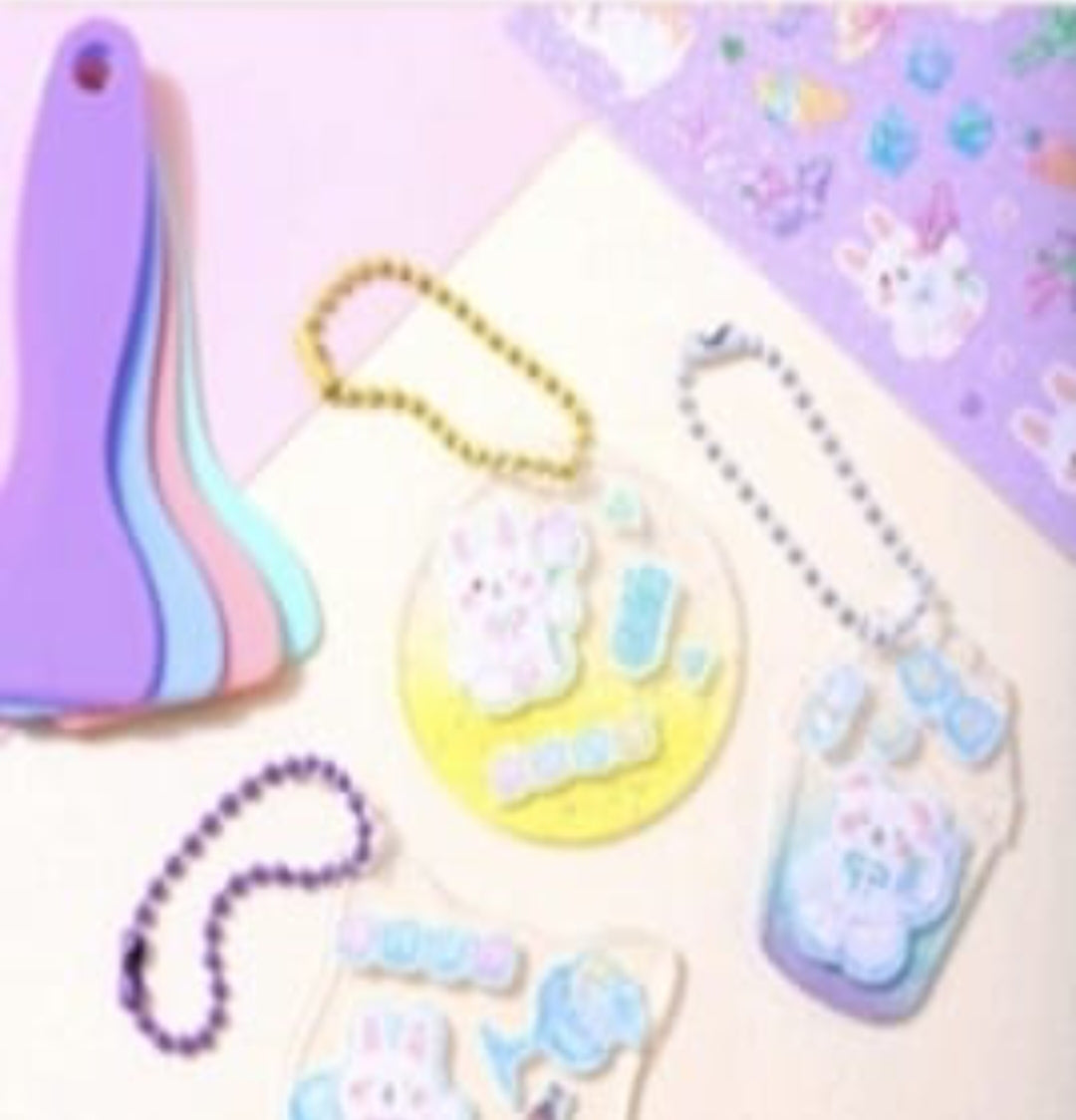 Pastel-colored keychains with cartoon character designs on a light purple background