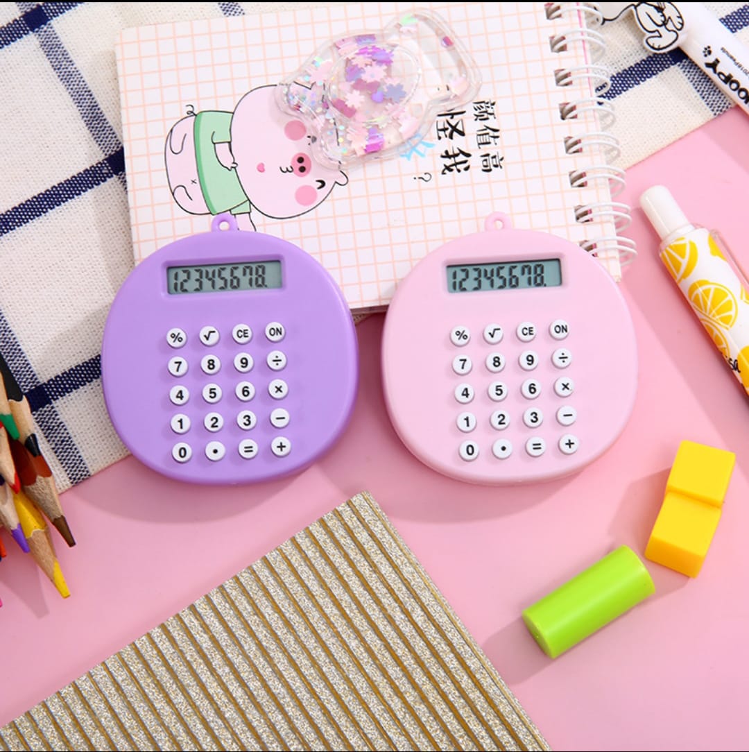 Two small calculators, one purple and one pink, on a pink surface with stationery items.