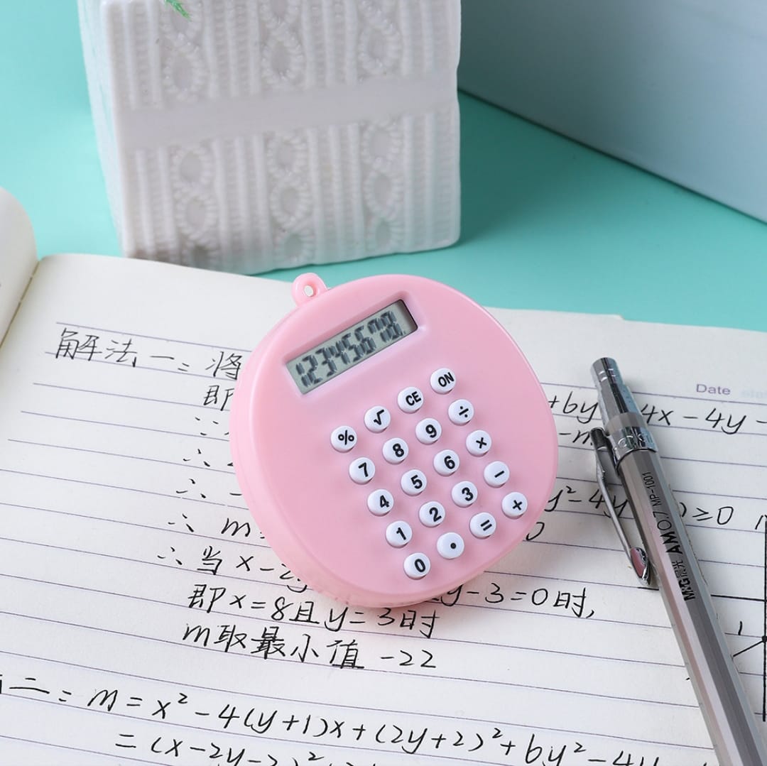 Pink calculator on a notebook with pens