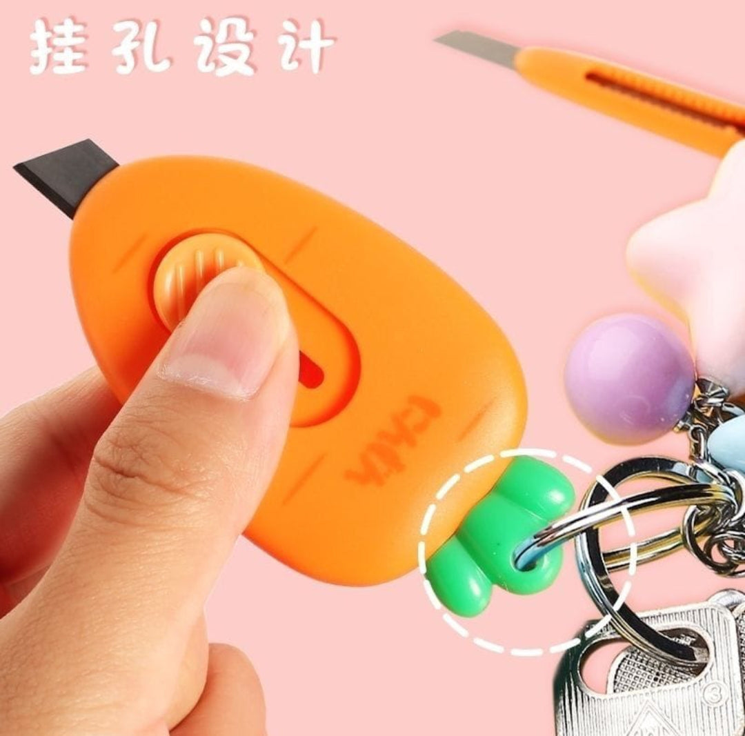 Orange keychain cutter held by a hand with a pink background