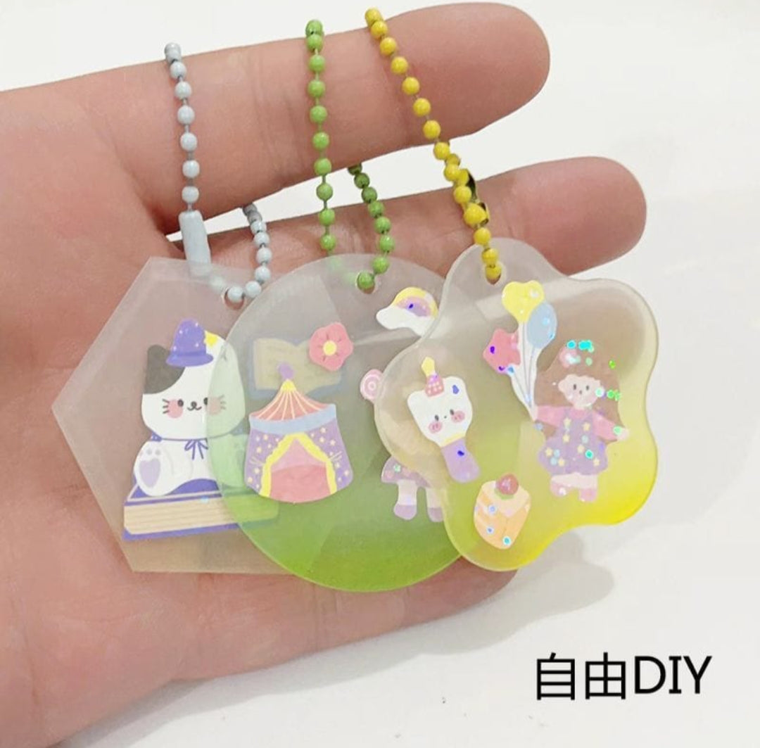 Hand holding two clear charms with cartoon designs and colorful beads on a white background