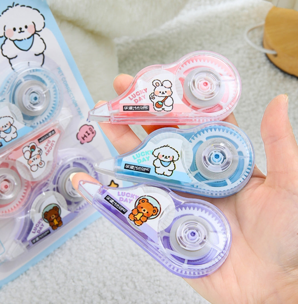 Hand holding correction tapes with cartoon designs on a textured surface