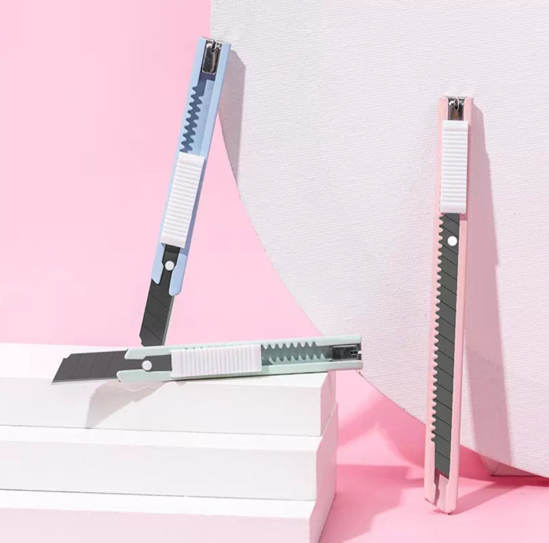 Three utility knives with different blade designs on a pink and white background