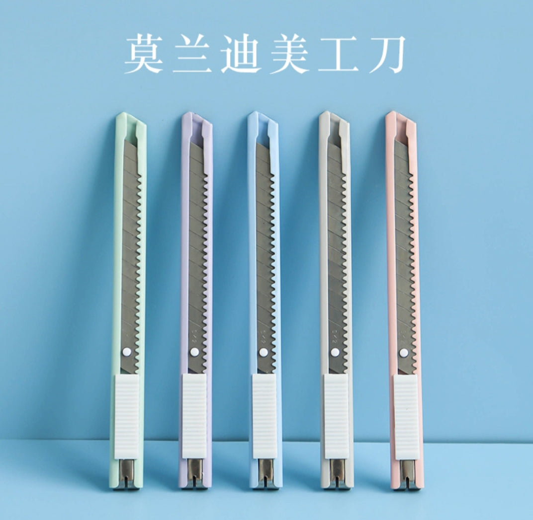 Five utility knives with different colored handles on a blue background