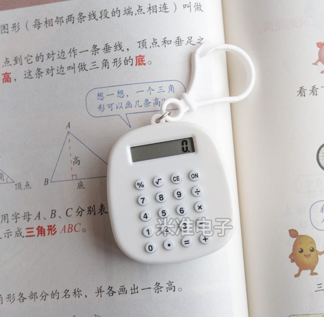 Small white calculator with a digital display on a book page